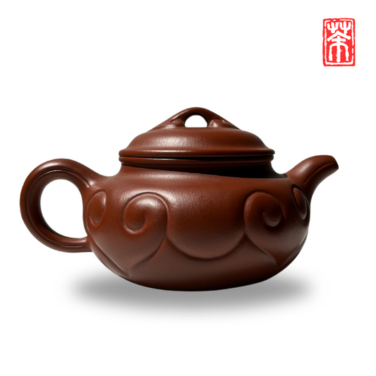 Ergänzen Sie Ihre Teekollektion mit dieser eleganten Yixing-Teekanne aus rötlichem Zisha-Ton. Die lebendige, helle Tonfarbe und das kunstvoll eingearbeitete Wolkenrelief machen sie zum Blickfang – perfekt, um die erdigen Aromen von Pu-Erh und dunklen Tees stilvoll zu genießen.